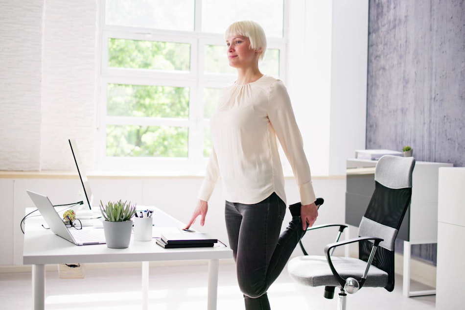 Frau macht Dehnungsübungen im Büro