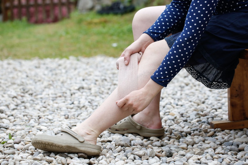Frau bindet sich Beine mit Verband