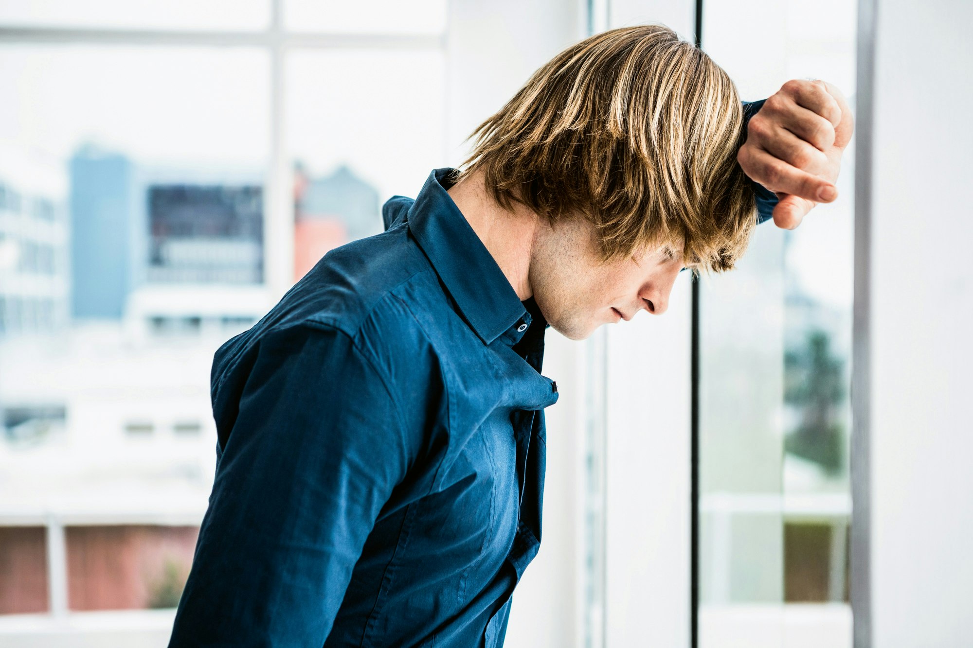 Erschöpfter Mann lehnt am Fenster