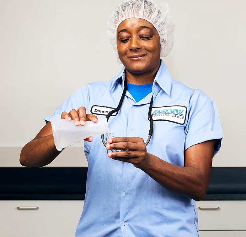 Woman in matrix uniform pouring liquid from beaker into test tube