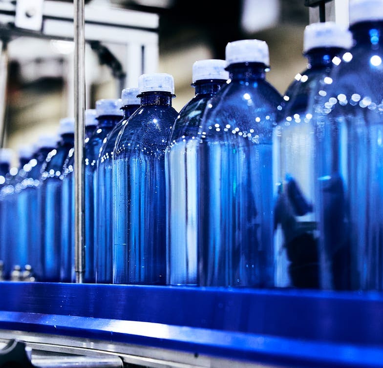 close up of a row of bottles on a belt in facility