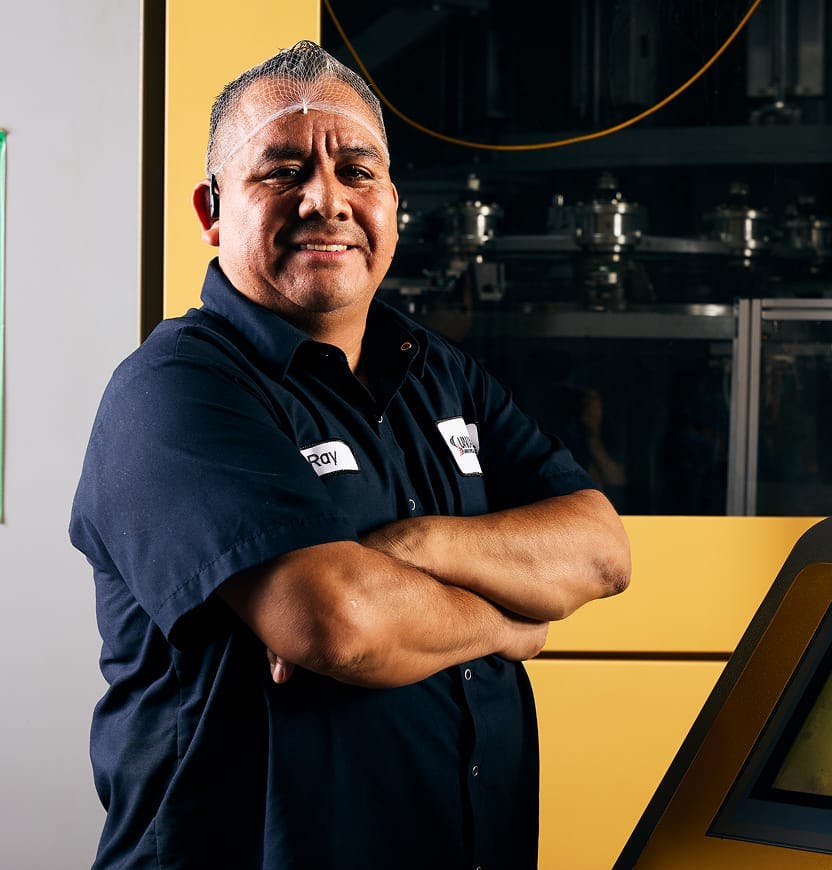 Employee standing with arms crossed wearing Matrix Bottling Group uniform