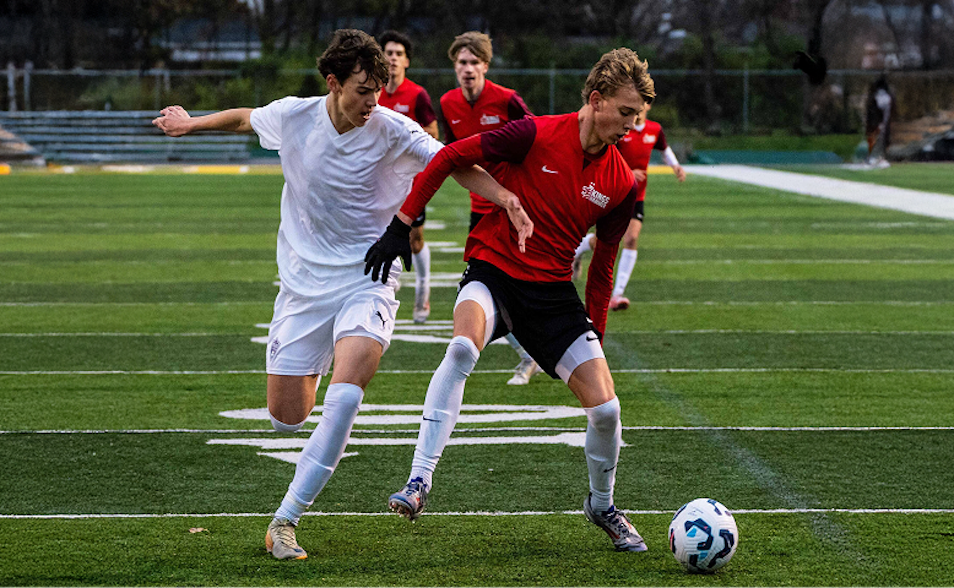 Two soccer players shown dueling for the ball