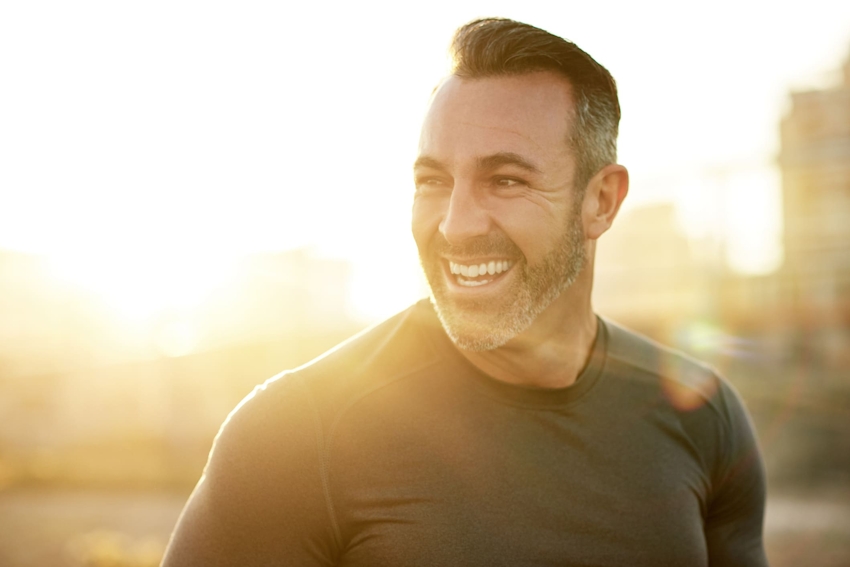man smiling with sunset behind him