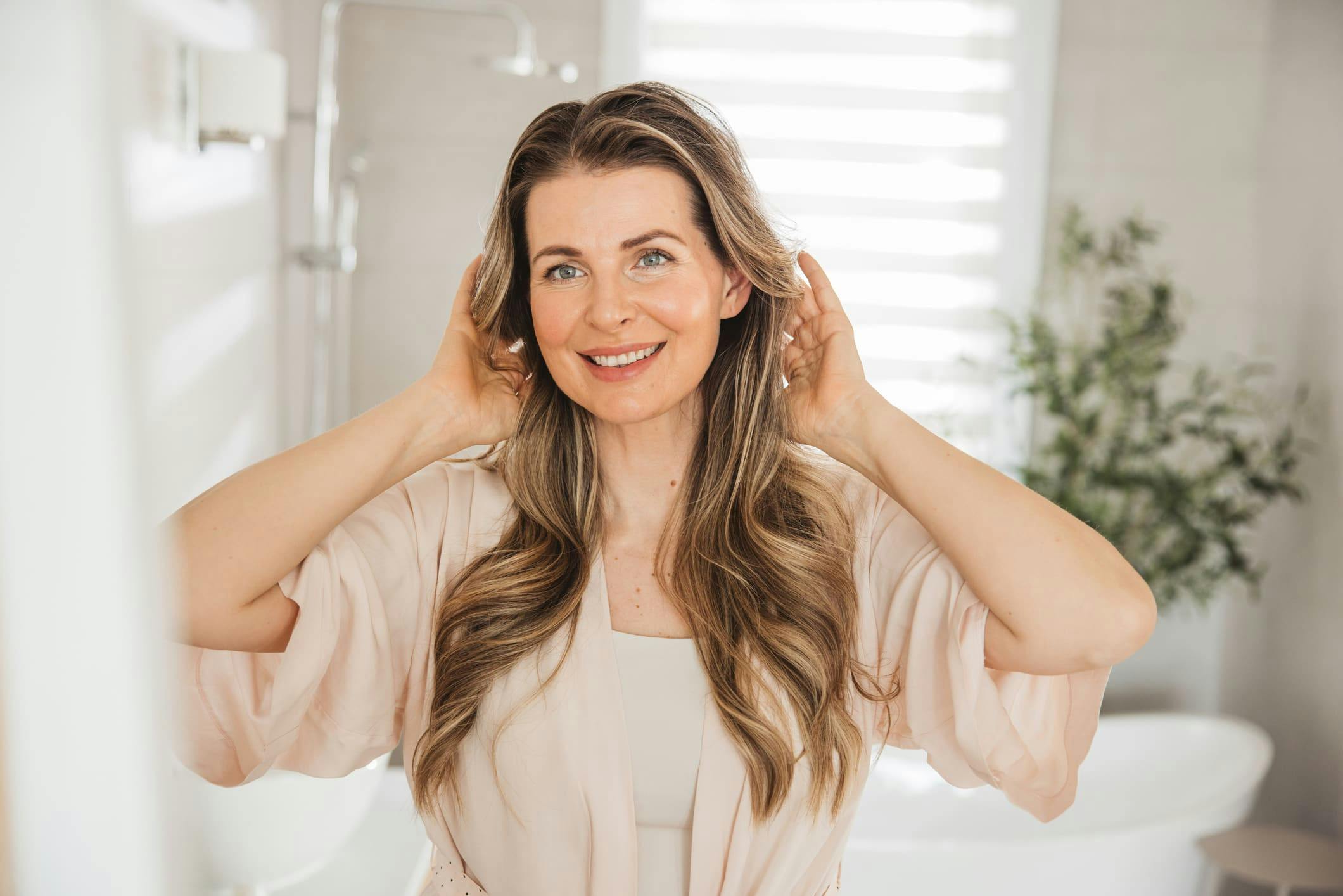 woman looking in mirror and touching her hair