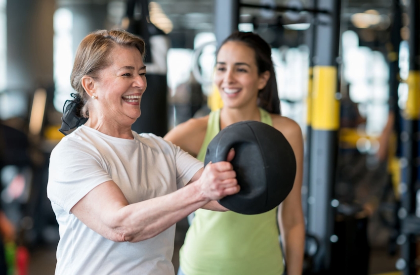 woman at the gym helping another woman work out