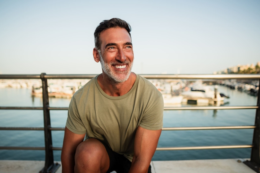 man smiling leaning down next to railing