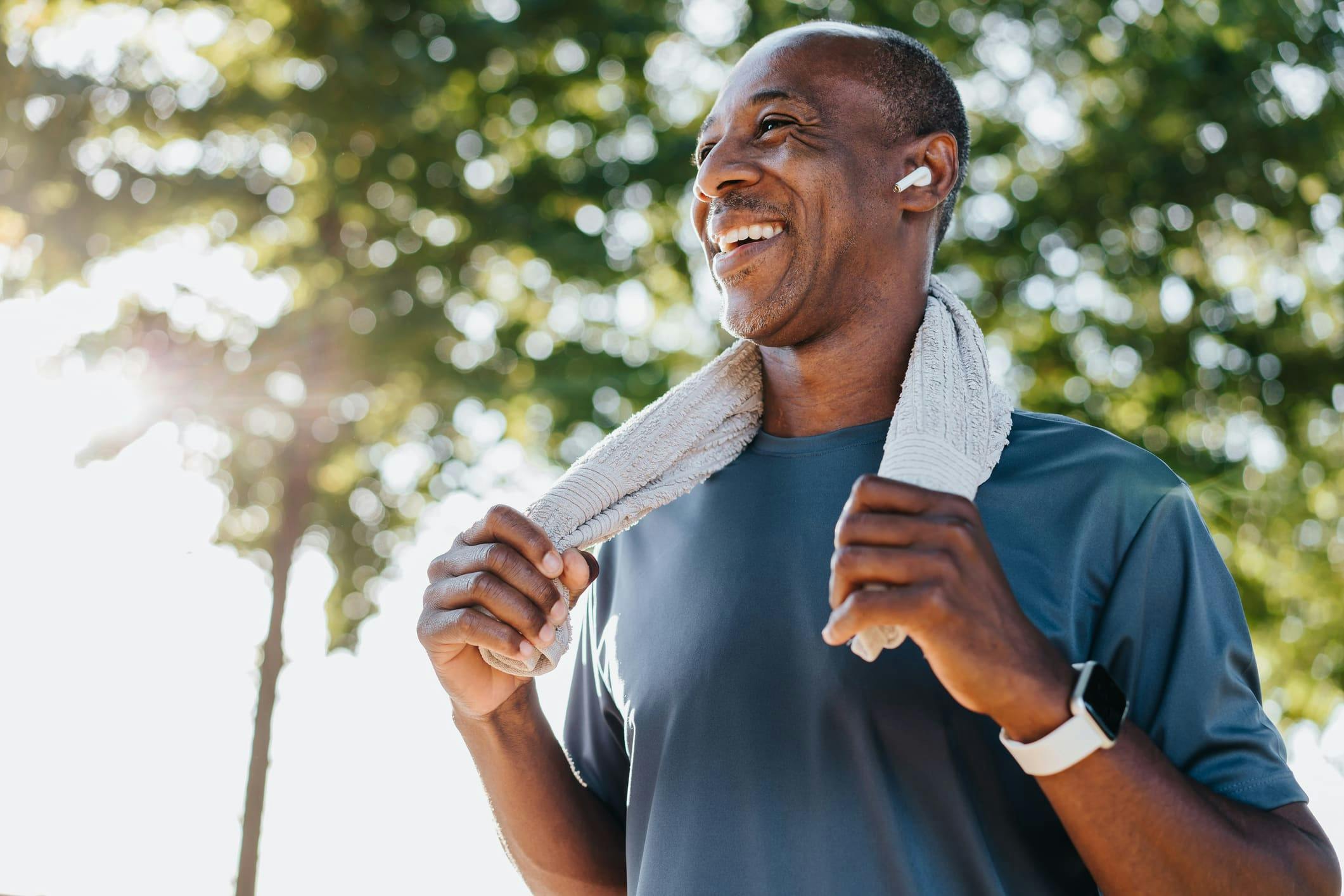 man smiling with small towel laying across the back of his neck