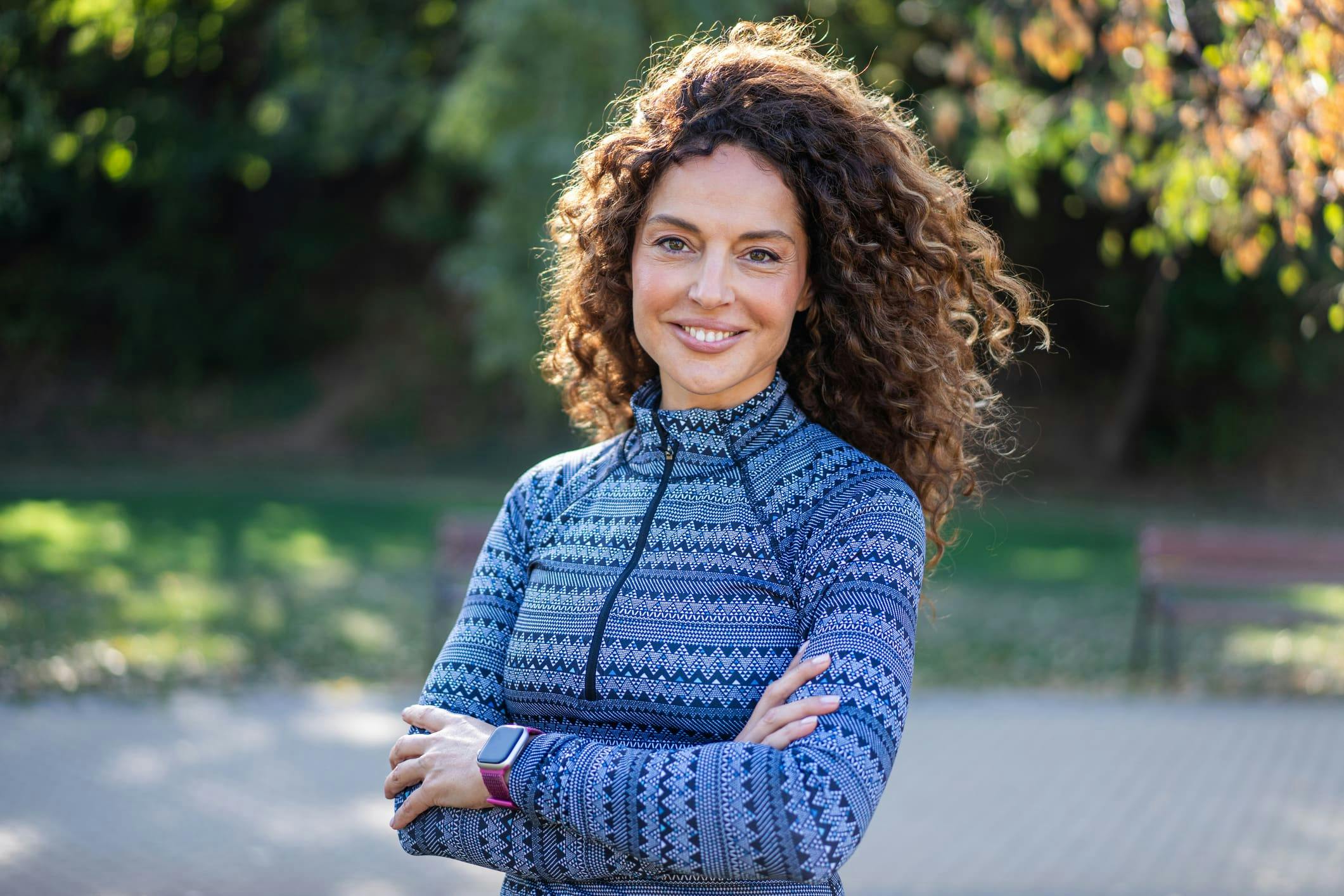 woman outside with her arms crossed and smiling