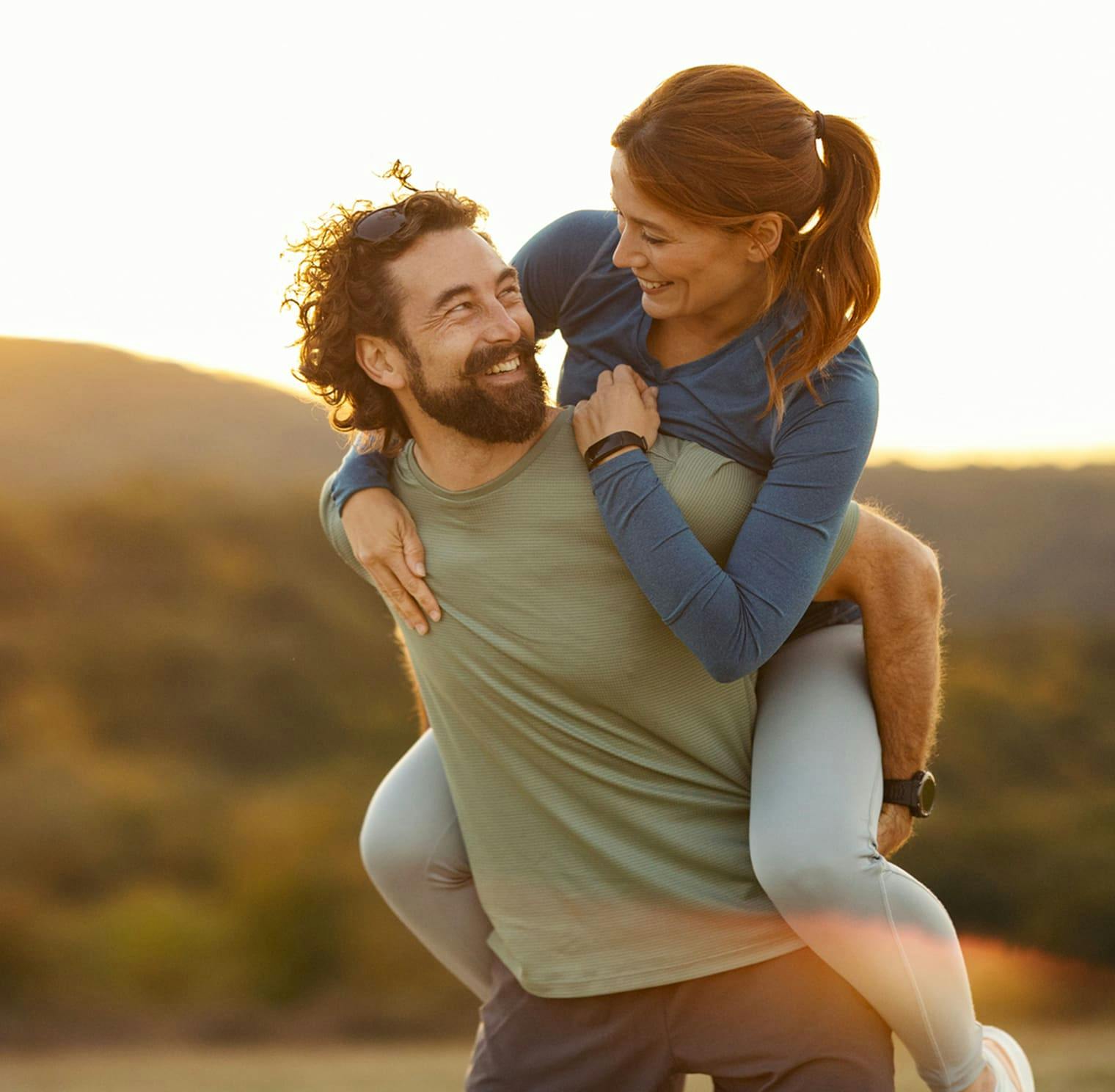 couple smiling while woman is on the mans back