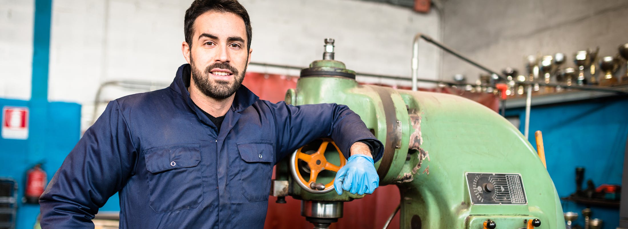 Man in work outfit leaning on a piece of equipment