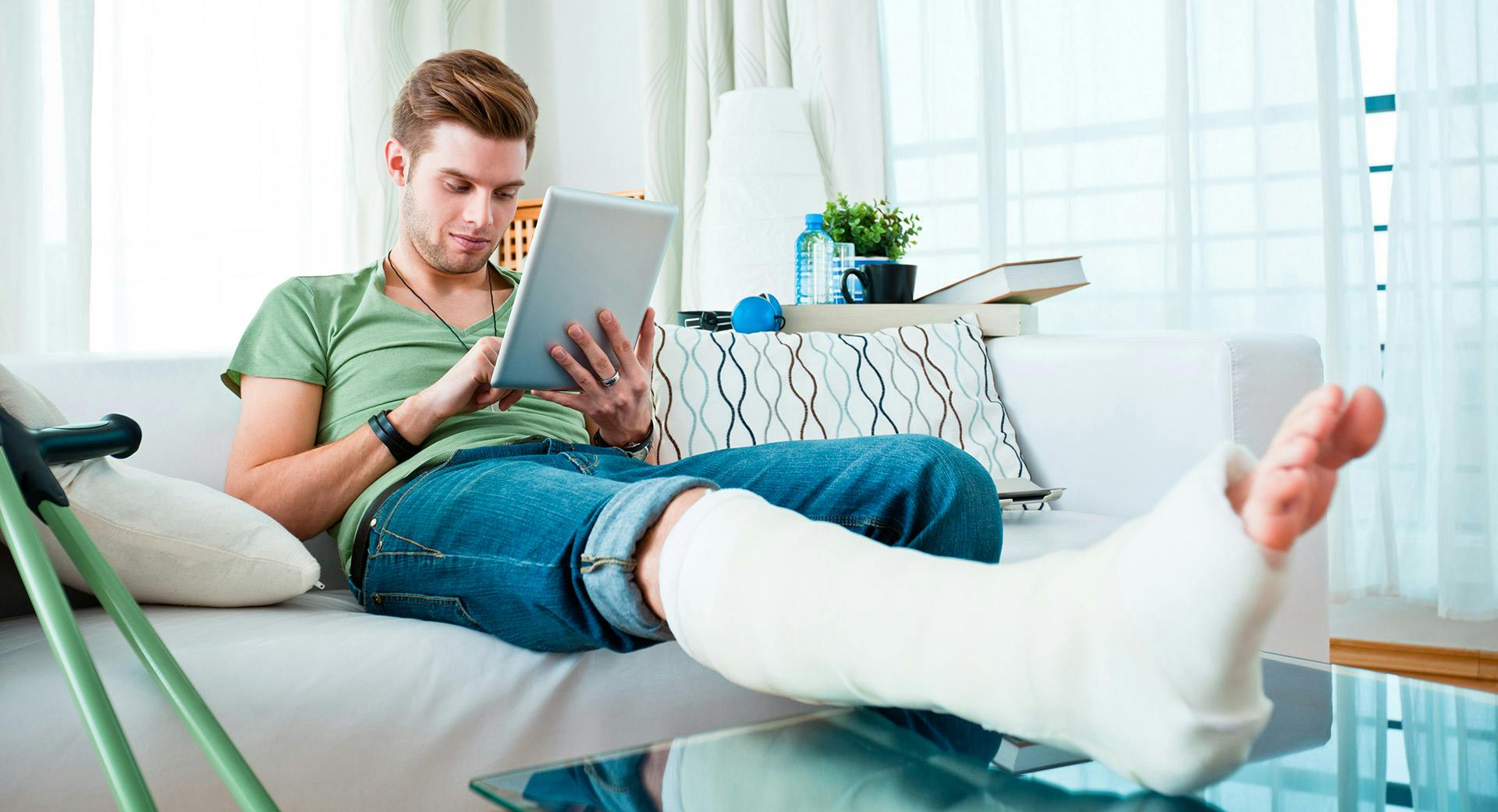 Injured man with lower leg cast resting on coffee table