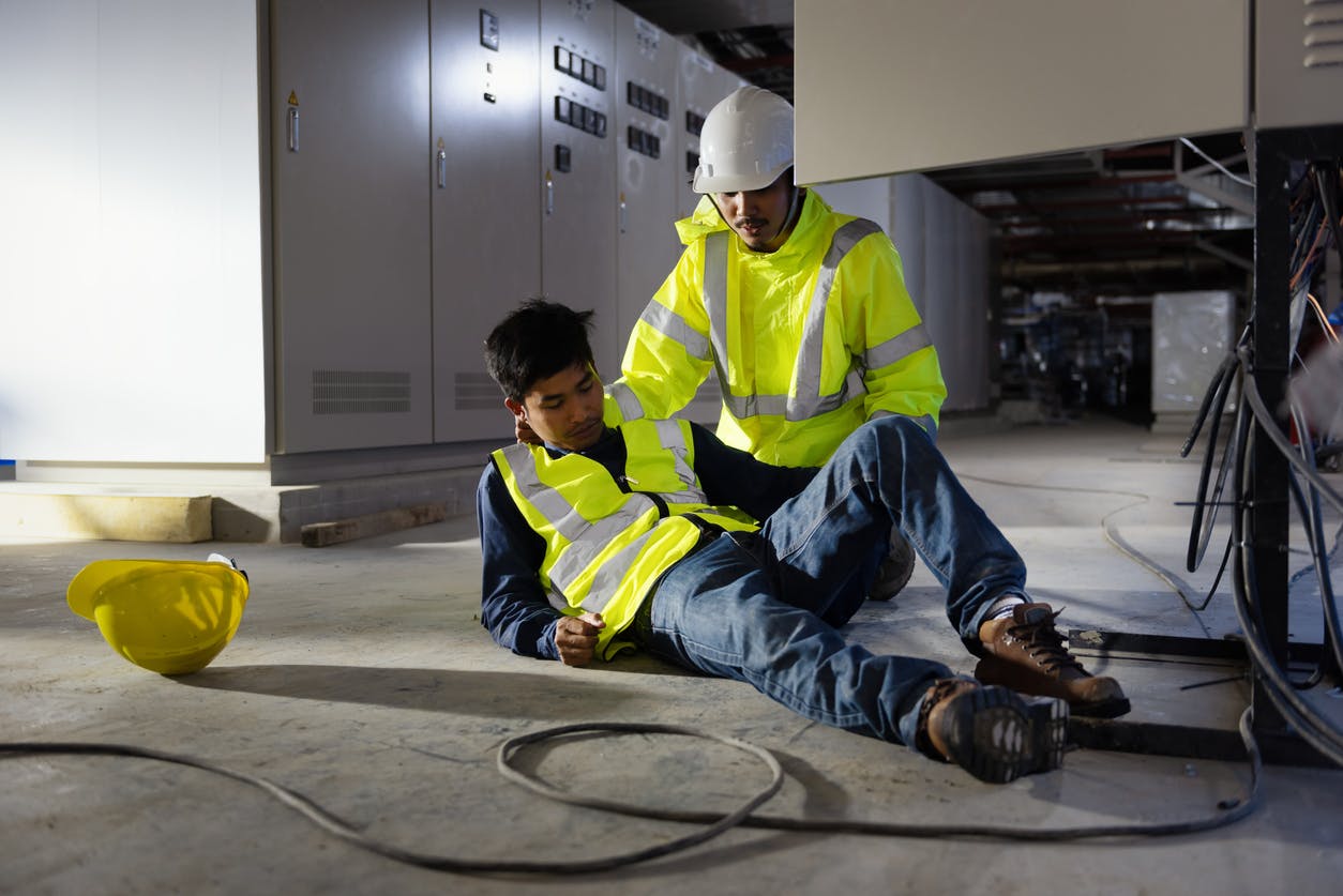 Two workers on a construction site, one injured