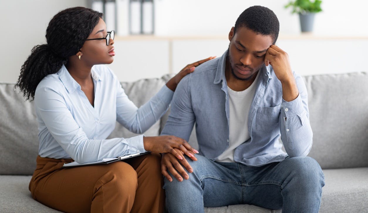 Woman comforting distressed man on couch