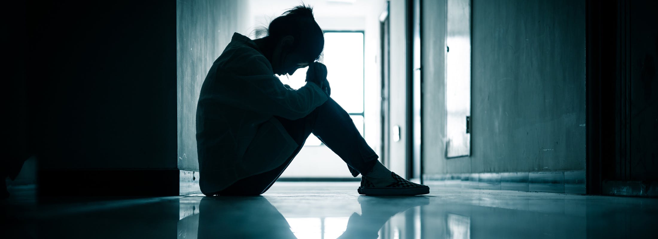 Shadowy image of a woman sitting in a hallway