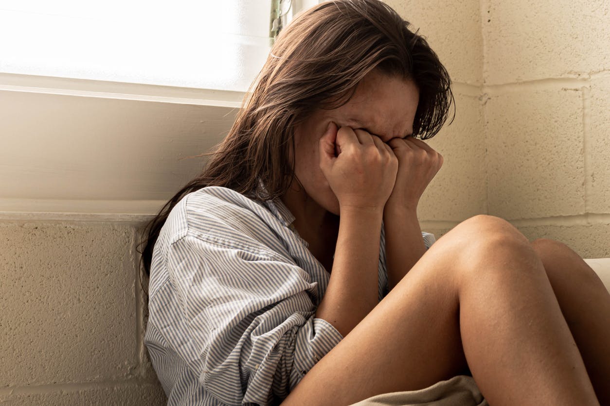 Woman sitting & crying in a corner.