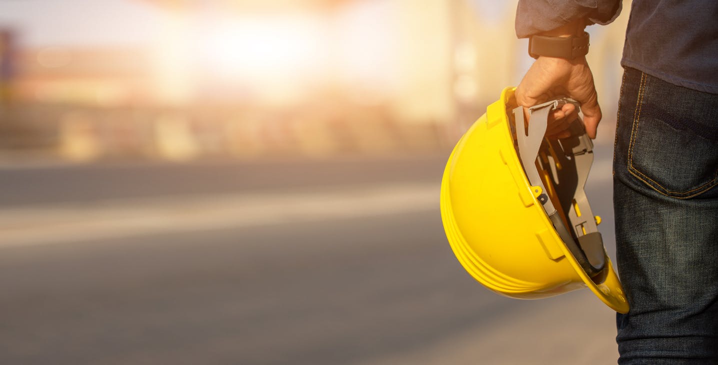 Man standing with a yellow construction helmet.