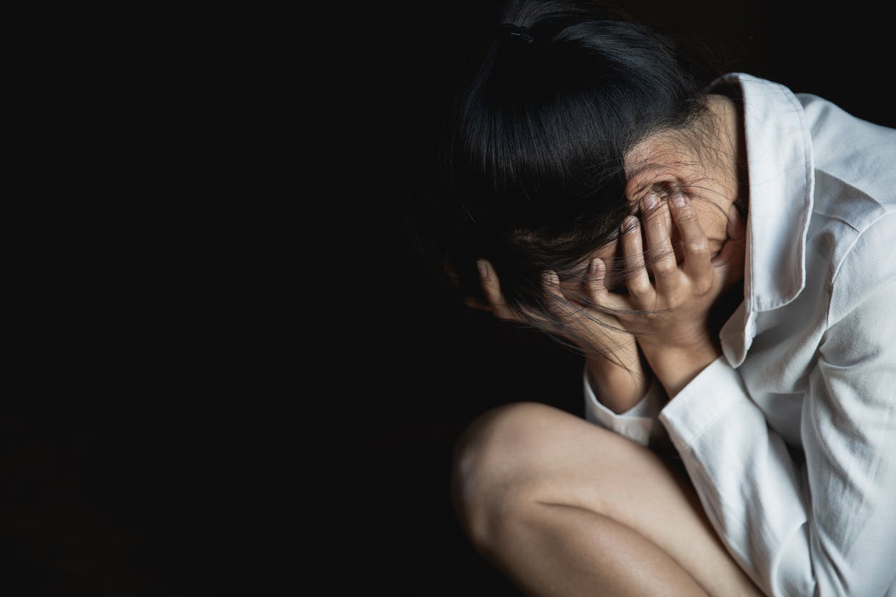 A sad looking woman covering her face with her hands.