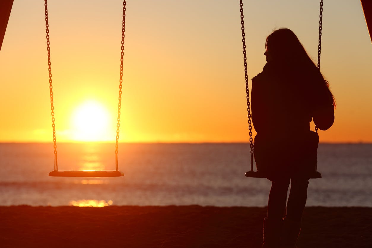 Woman sitting on a set of swing by herself