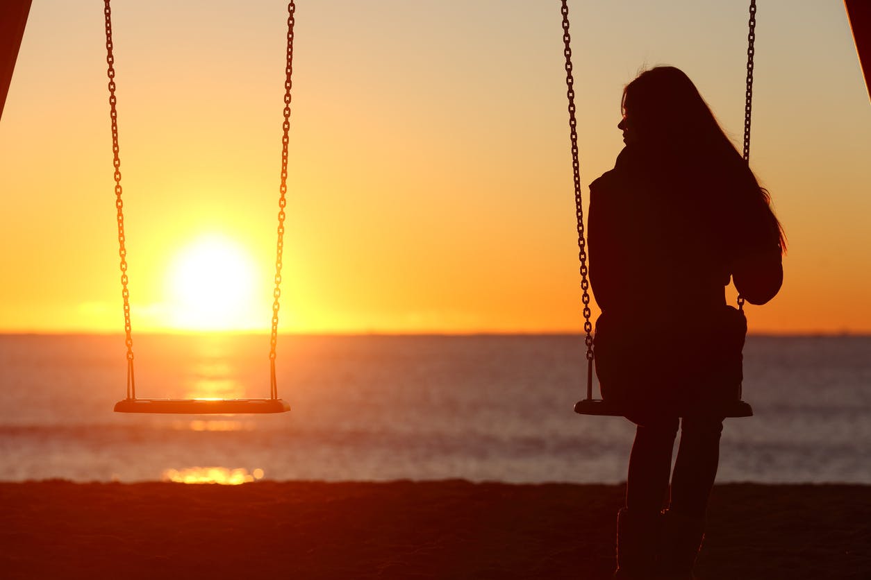 Woman sitting on a set of swing by herself