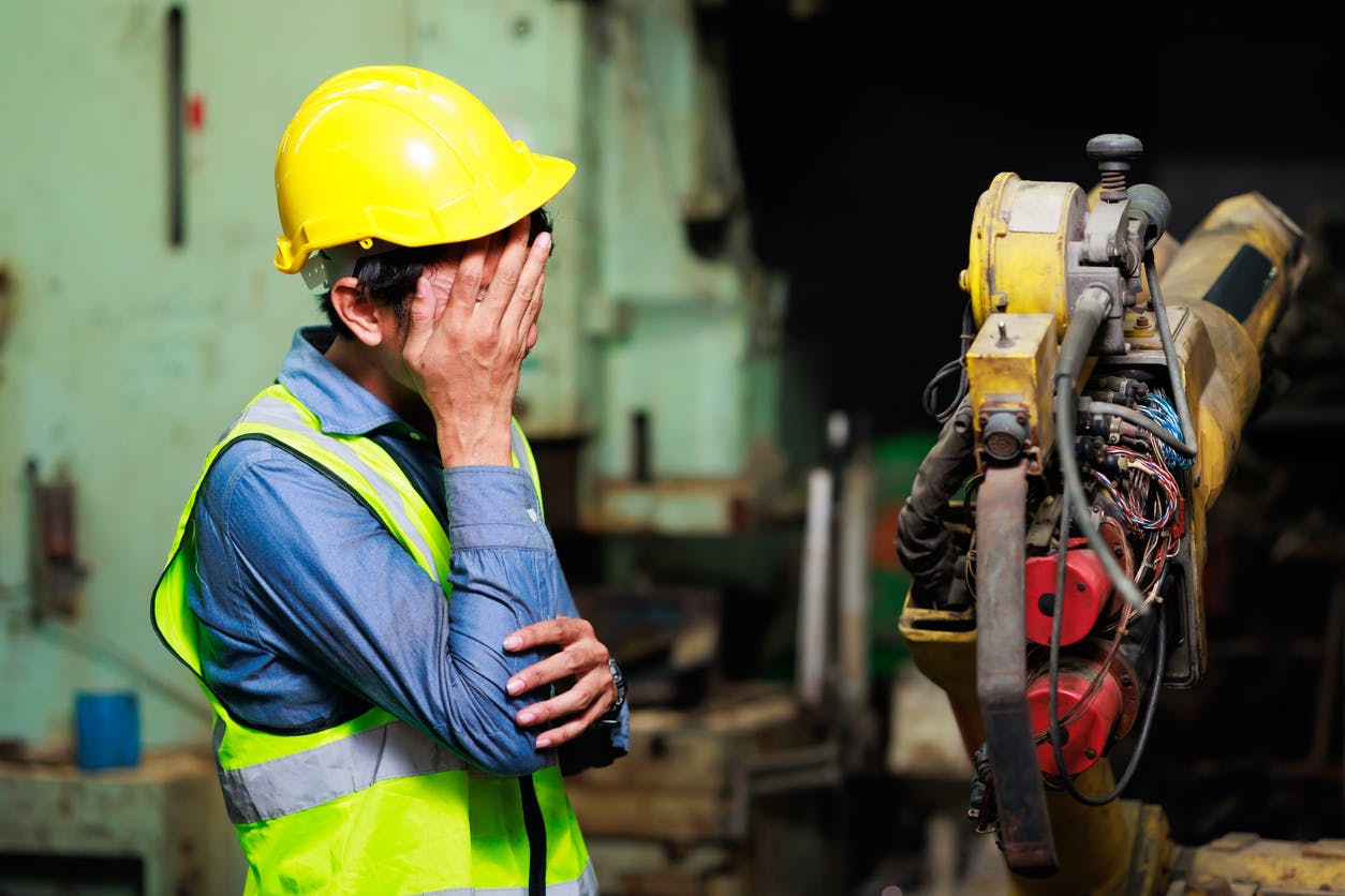 Construction worker holding his eye next to equipment