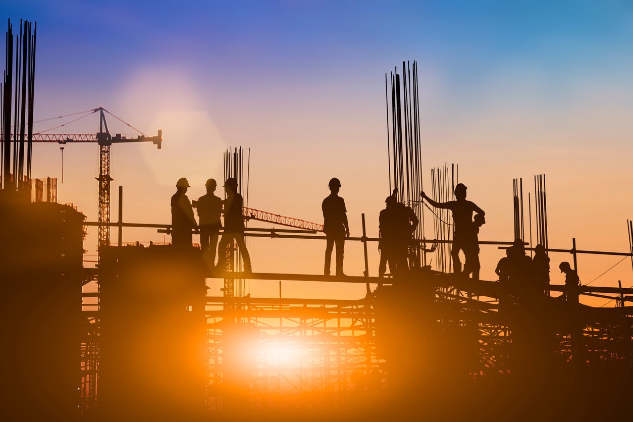 Construction site, with workers, at sunset