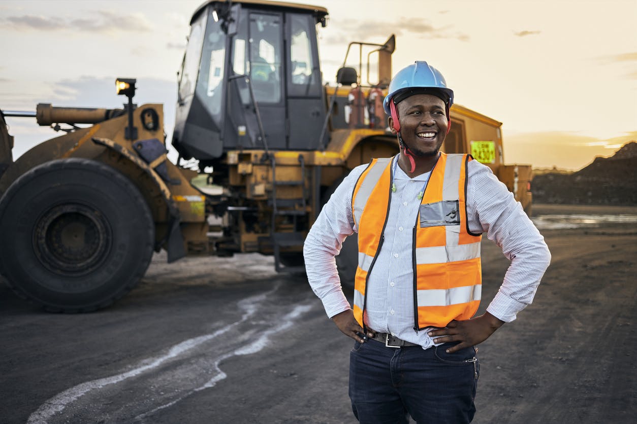 Construction worker standing next to a tractor