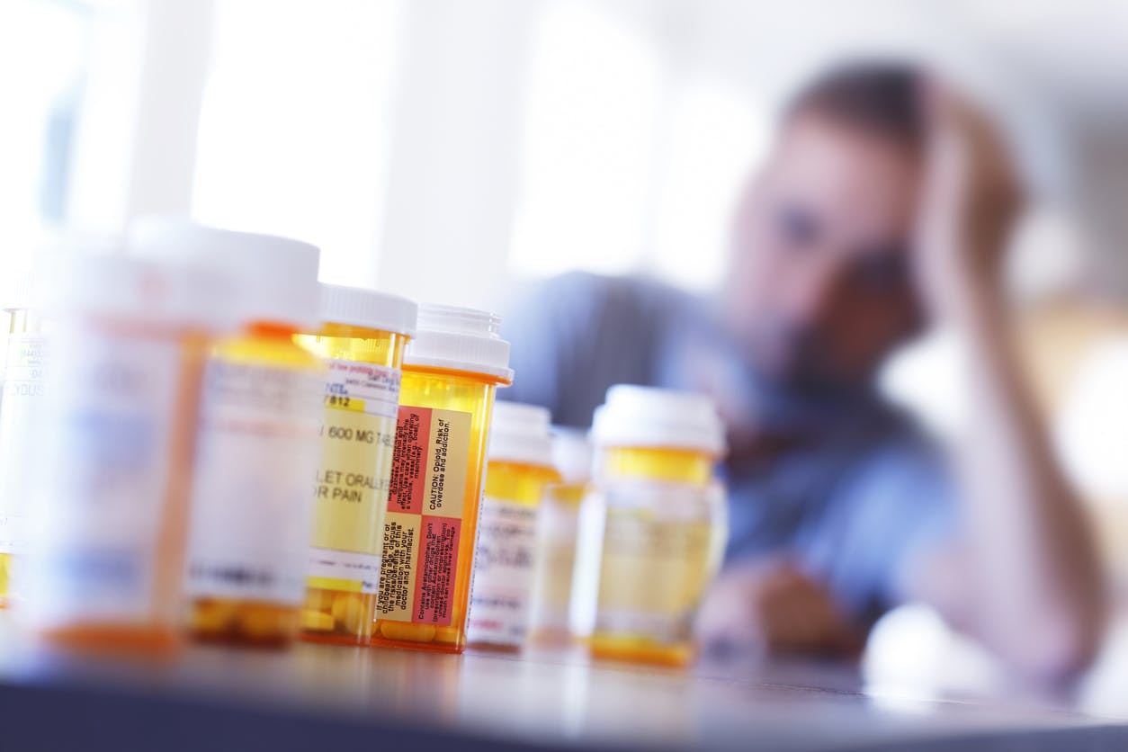 Man looking distraught as he looks at bottles of pills