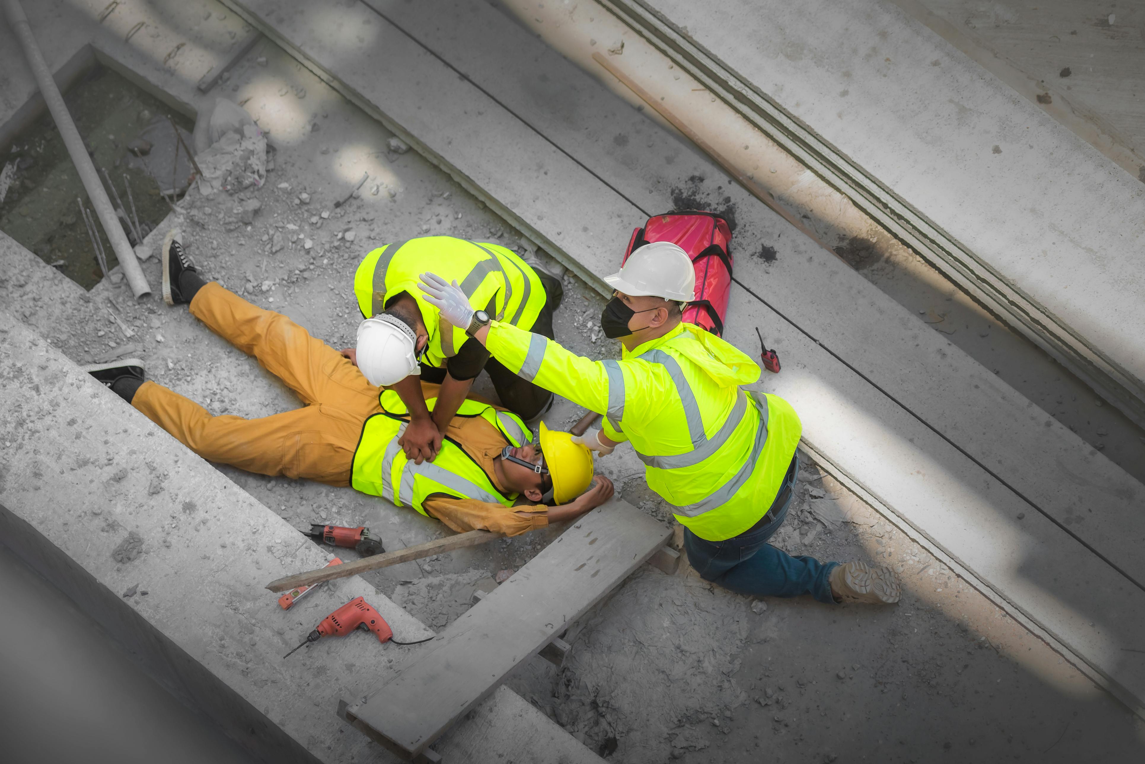 Construction worker injured on a construction site being aided by other construction workers