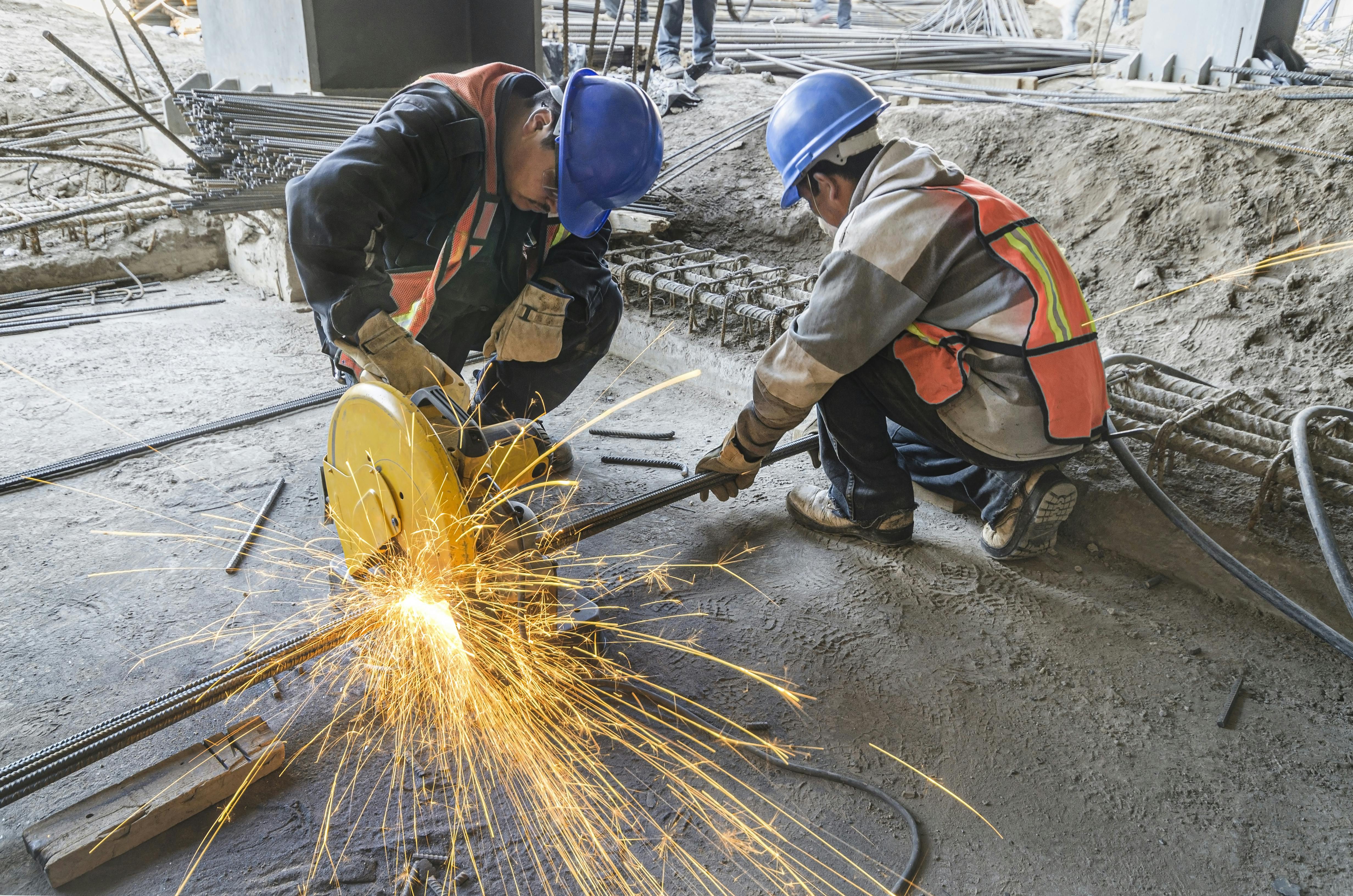 Construction workers cutting a pipe