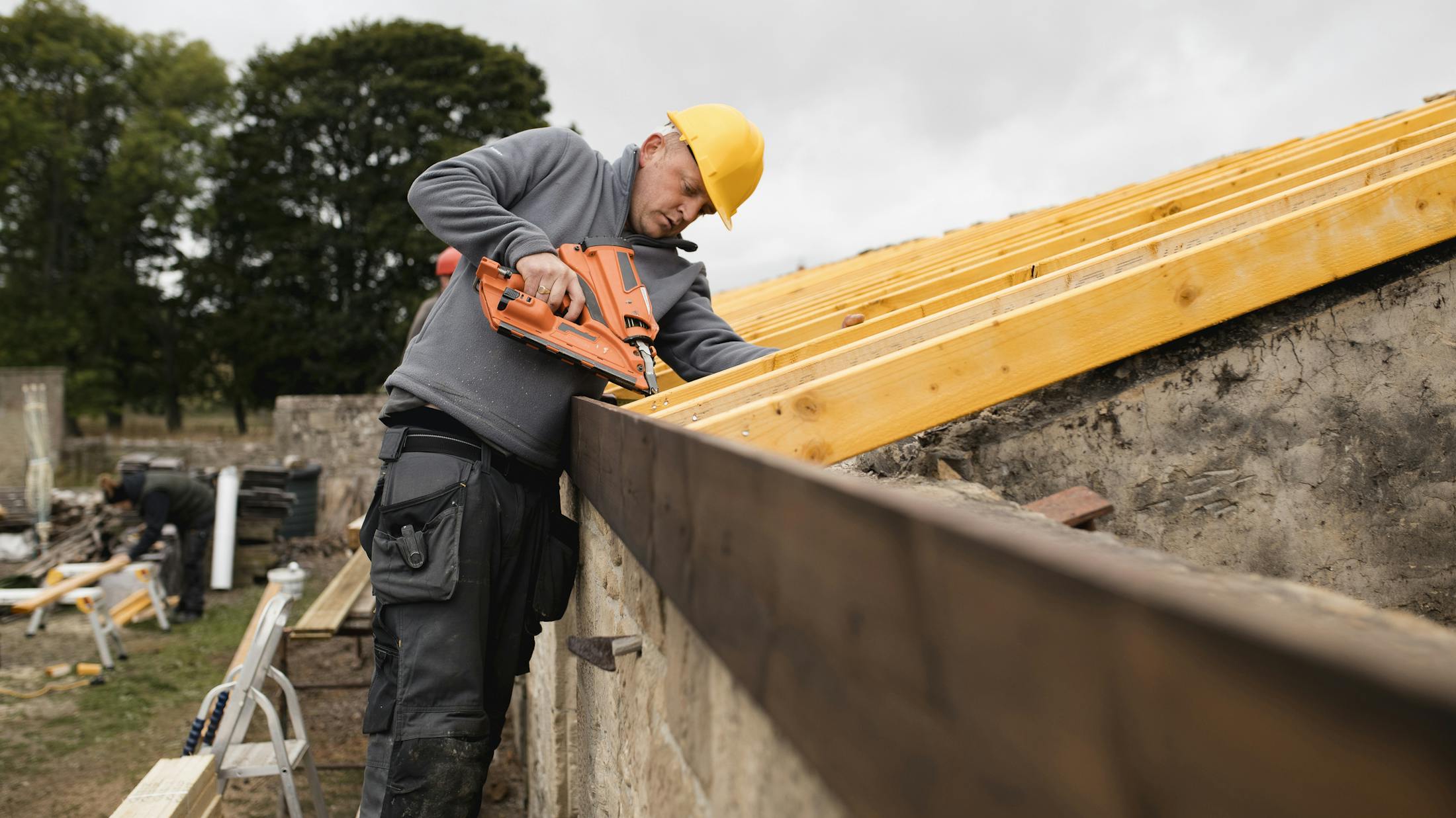 man using nail gun on a house