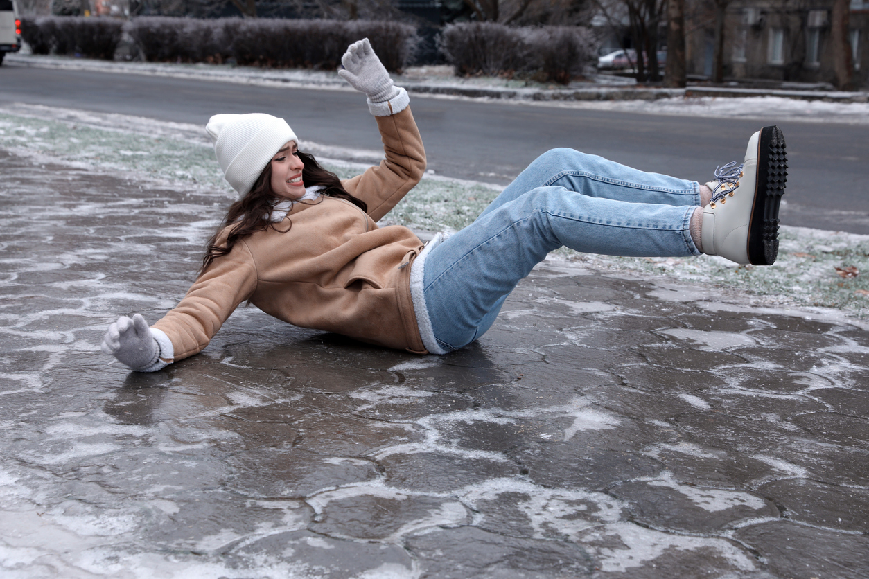 Woman falling down on icy sidewalk