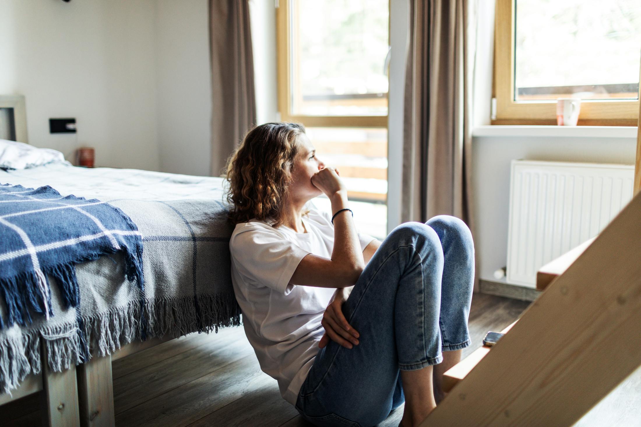 sad young woman at the end of a bed
