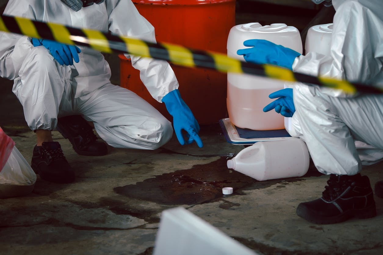 People in hazmat suits looking at spilled chemicals