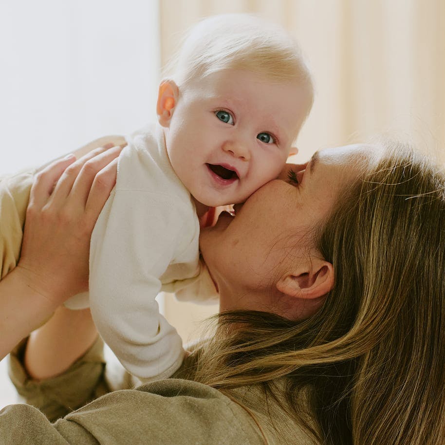 A woman holding and kissing a baby