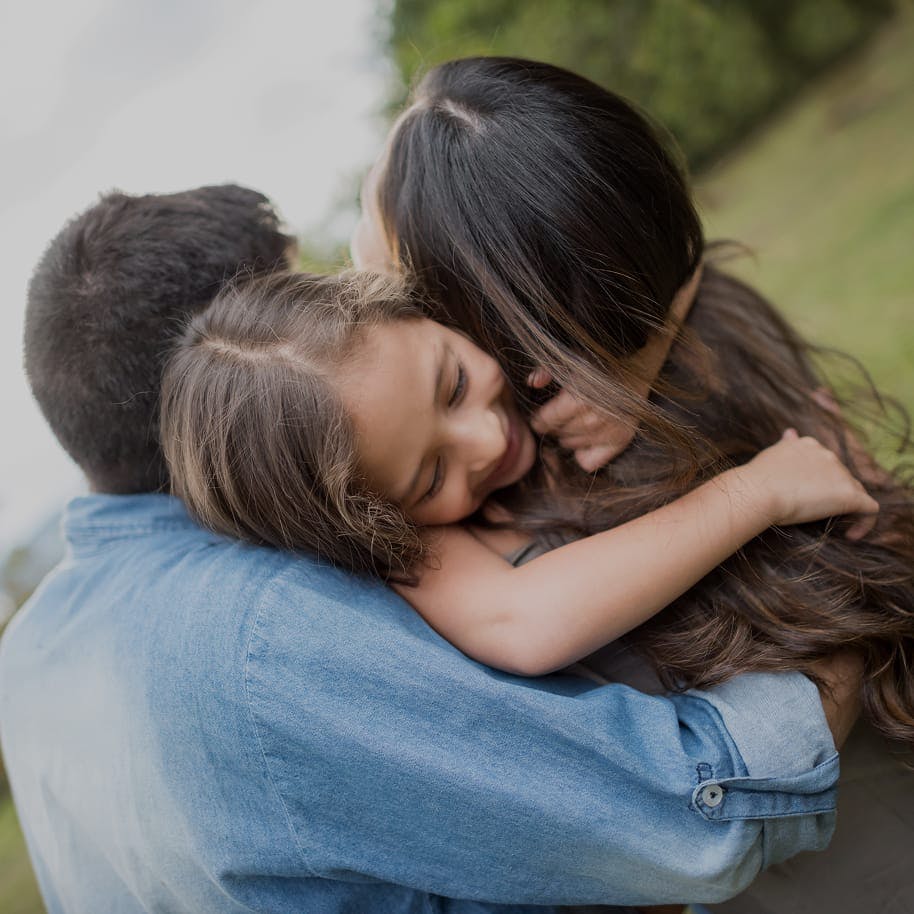 A little girl hugging her parents