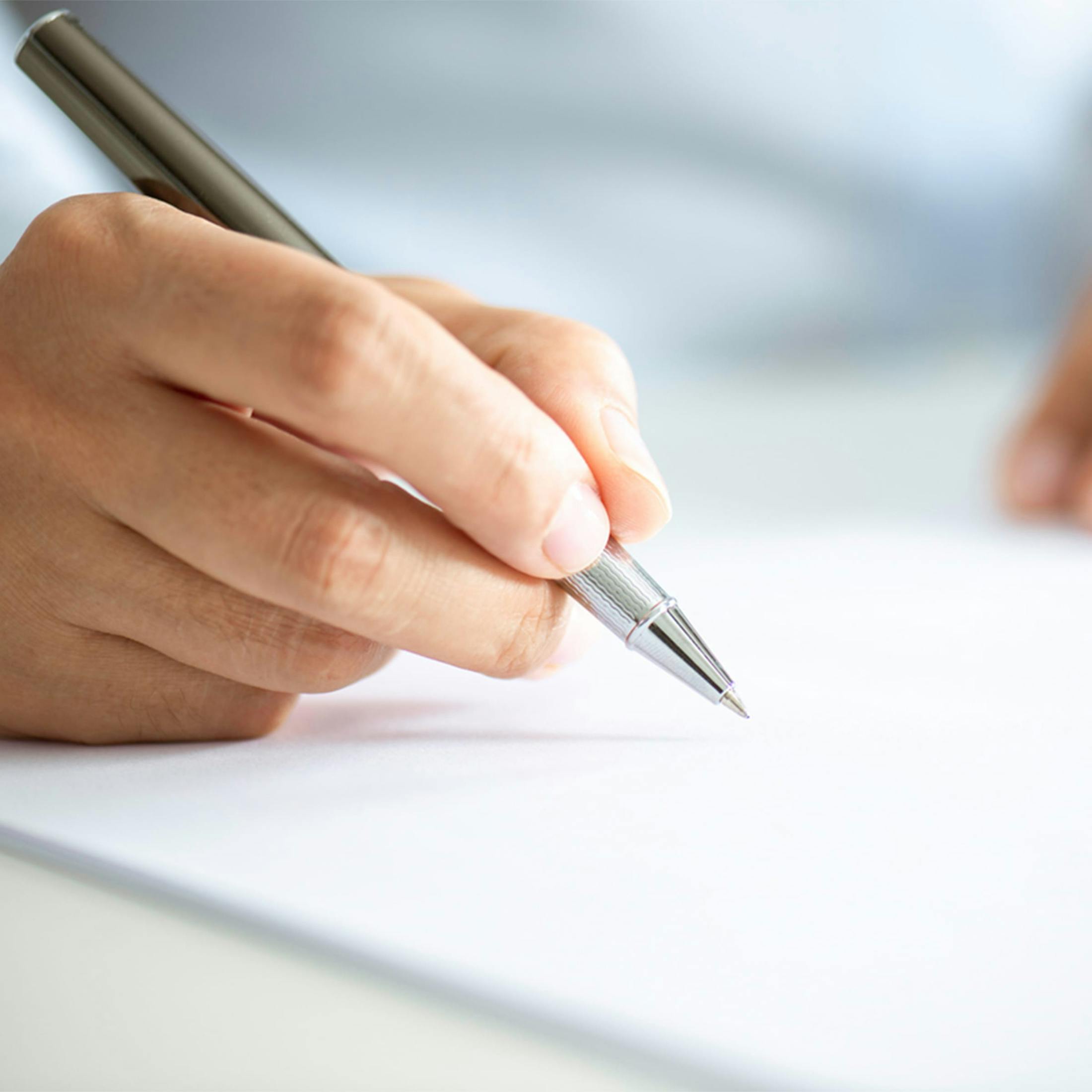 hand holding pen writing on paper