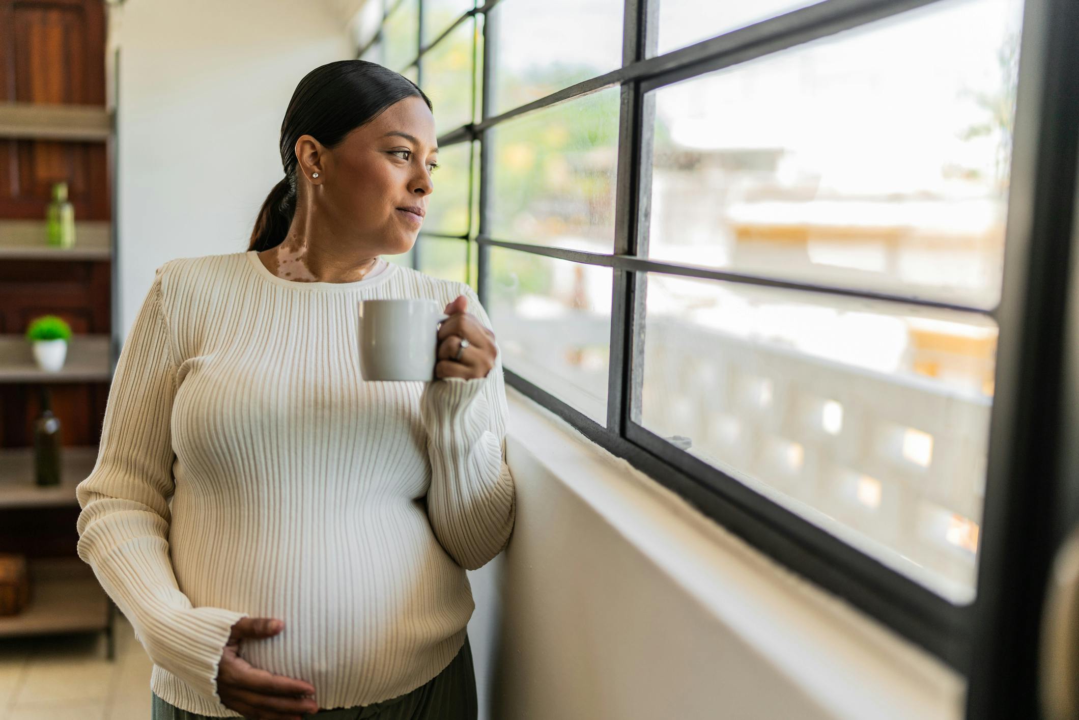 Young pregnant contemplating and drinking tea at home