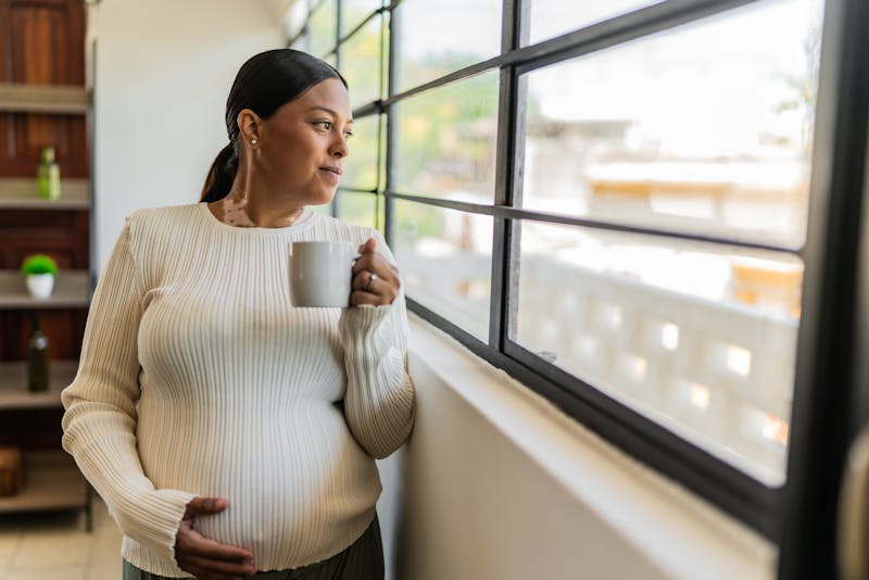 Young pregnant contemplating and drinking tea at home