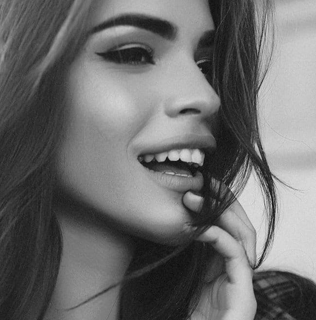 Woman looking to the side with her mouth parted open slightly, wearing makeup