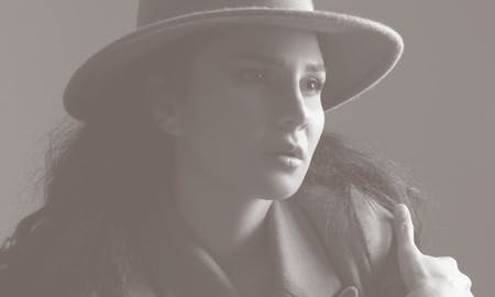 Face of a woman wearing a brimmed hat and coat.