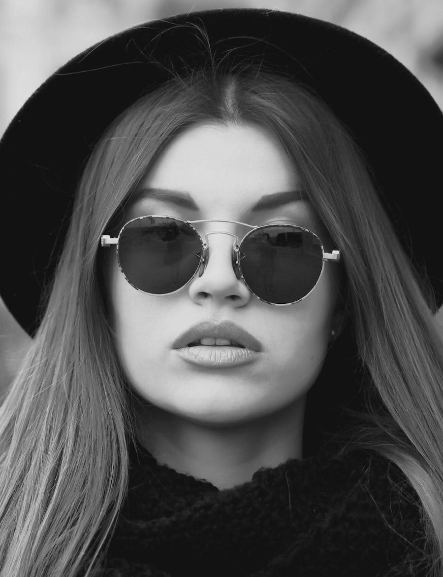 Woman with sunglasses and a brimmed hat.