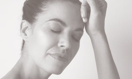 A woman with eyes closed and left wrist on her face.