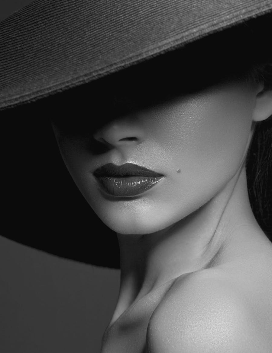 Woman with a brimmed hat, eyes covered in shadow.