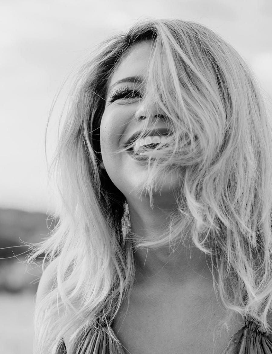 Woman smiling, face half-covered with her hair.