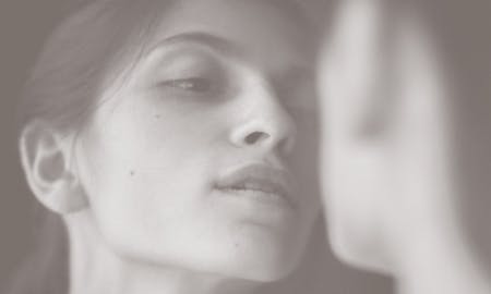 Woman looking at her face in mirror after microdermabrasion