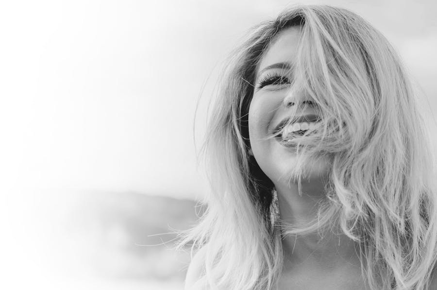 Woman smiling, half her face covered by her hair.