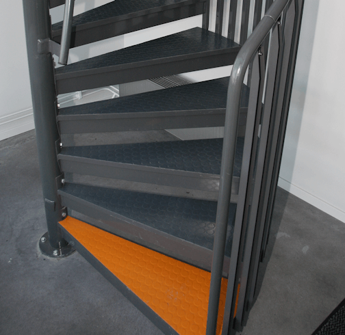 Inspiration für farbliche Pulverbeschichtung Ausschnitt einer Spindeltreppe mit orangefarbener Stufe als Kontrastmarkierung