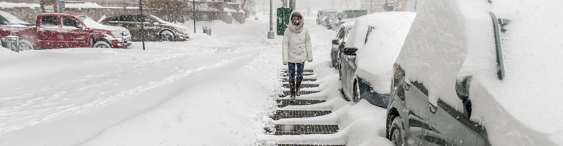 Eine Frau läuft auf Gitterrost auf schneebedeckten Straßen.