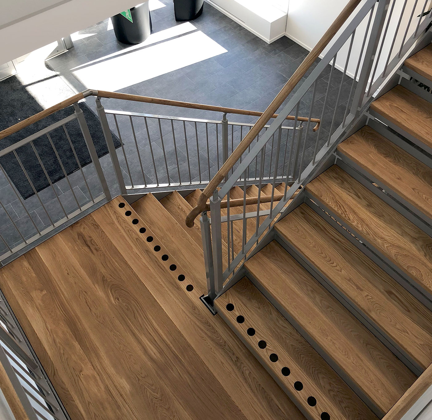 Gerade Treppe drinnen mit Holzstufen und Handlauf- und Kontrastmarkierung